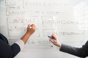 Photo of two people writing on a whiteboard