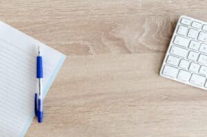 Photo of notebook, pen, and keyboard on a clean table