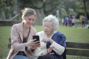 Elderly woman with her granddaughter looking at mobile phone in the park