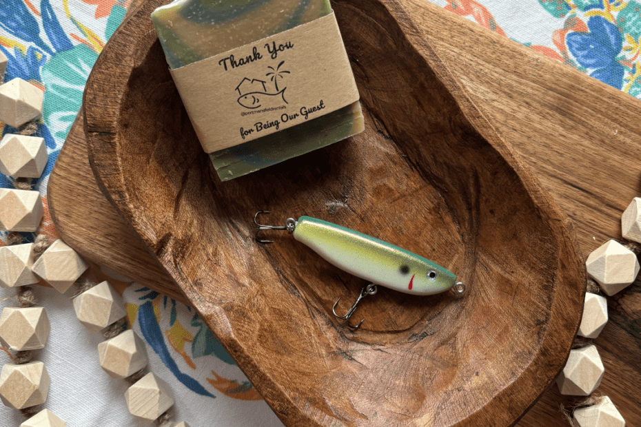 Flatlay photo of a bar of goat's milk soap and a handcrafted fishing lure