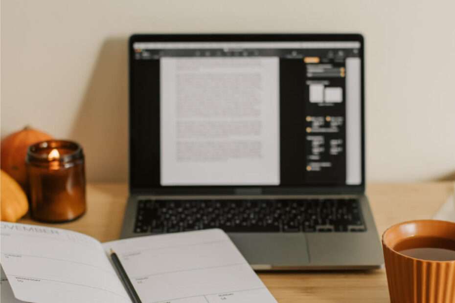 Laptop, notebook, and a cup of coffee on a desk